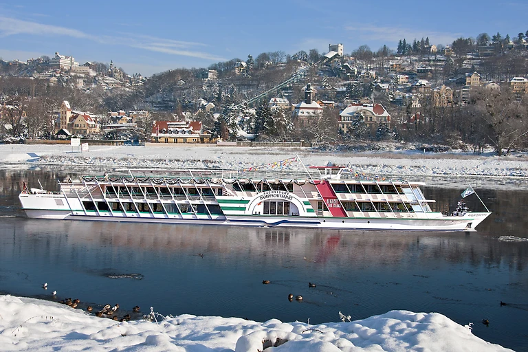 Salonschiff „August der Starke“ der Sächsischen Dampfschiffahrt auf der Elbe vor verschneiter Winterlandschaft, im Hintergrund Loschwitz und Weißer Hirsch