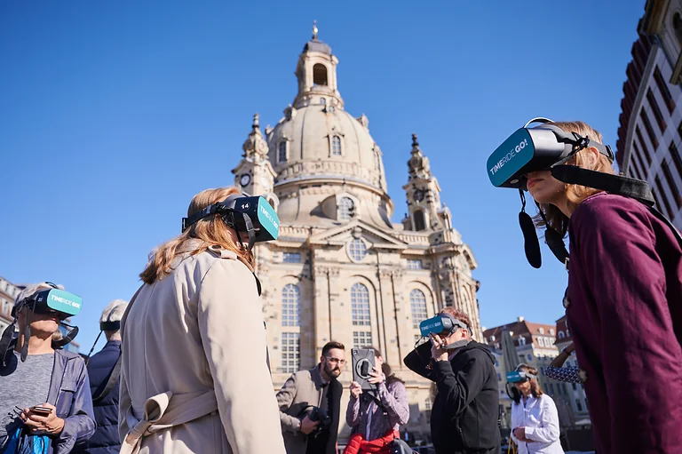 Teilnehmende von TimeRideGo! stehen mit VR-Brillen vor der Frauenkirche Dresden und erleben virtuelle Stadtgeschichte.