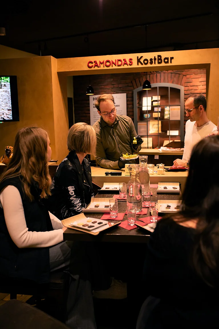 Teilnehmer einer Schokoladenverkostung in der CAMONDAS KostBar in Dresden mit Pralinen und Feinkostproben.