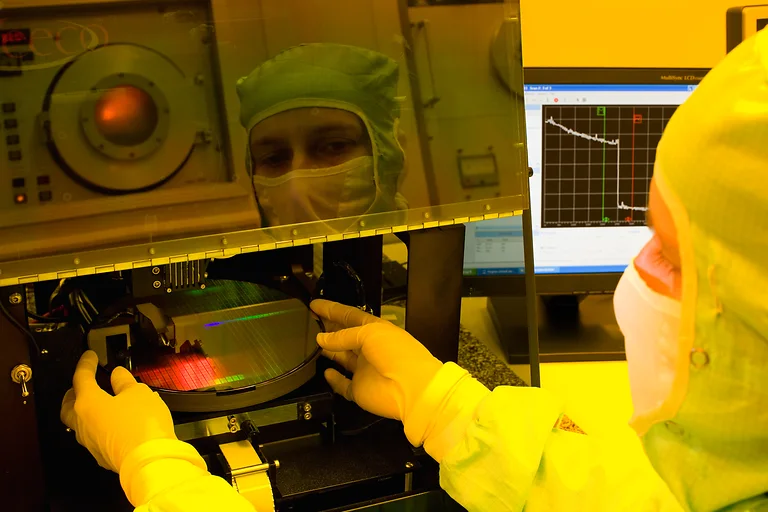 Forscher mit Schutzanzug, Maske und Handschuhen untersucht dünnste Schichten und Nanostrukturen.