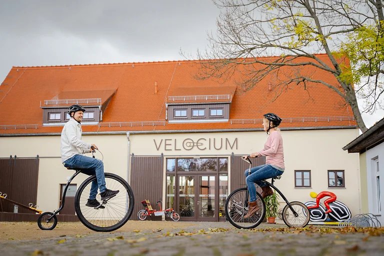 Zwei Personen probieren vor dem Fahrradmuseum VELOCIUM in Weinböhla historische Fahrräder aus.
