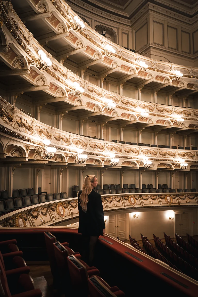 Besucherin blickt vom oberen Rang in den prunkvollen Zuschauerraum der Semperoper Dresden.