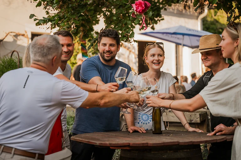Gruppe genießt Wein im Weingut Haus Steinbach in Dresden Elbland und stößt gemeinsam auf den Tag an.