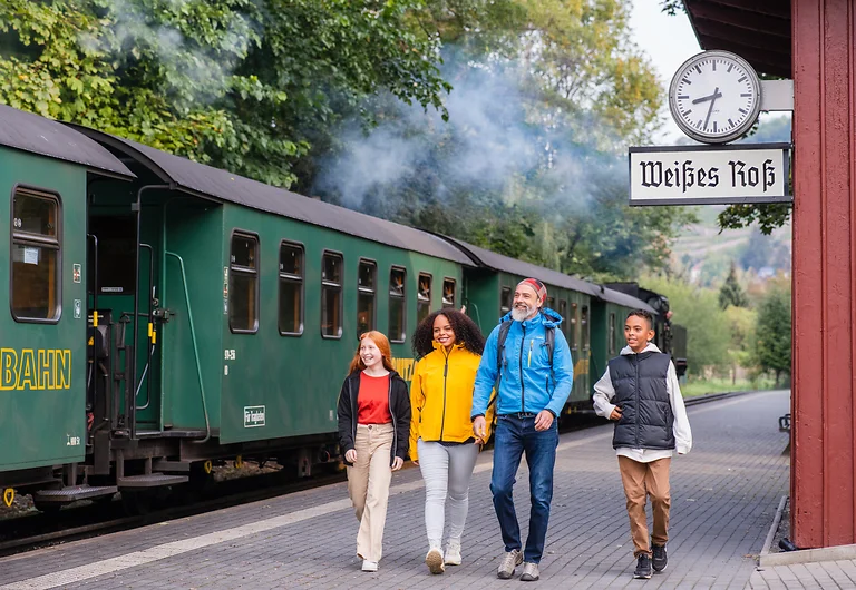 Familie mit zwei Kindern am Haltepunkt Weißes Roß in Radebeul, bereit zur Fahrt mit der Lößnitzgrundbahn durch Dresden Elbland.