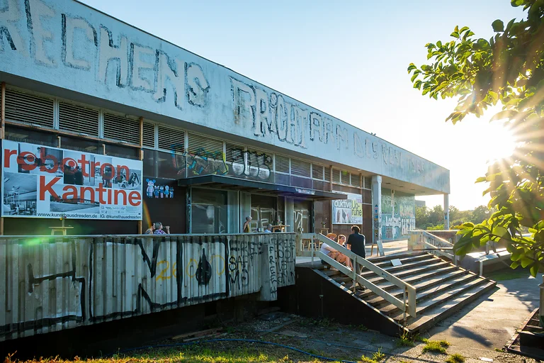 Fassade der Robotron-Kantine Dresden im Abendlicht mit Besuchern vor dem Kunsthaus Dresden.