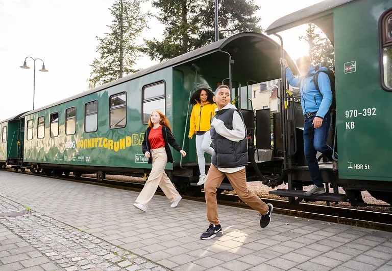 Vierköpfige Familie steigt an einem Haltepunkt der Lößnitzgrundbahn in Dresden Elbland aus.