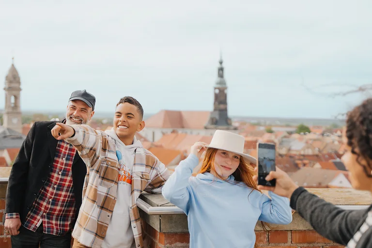 Mutter fotografiert Kind und Mann vom Friedensturm aus mit Blick auf Großenhains Dächer und Türme.