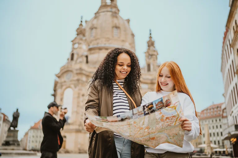 Mutter mit Tochter studiert einen Stadtplan vor der Dresdner Frauenkirche auf dem Neumarkt.