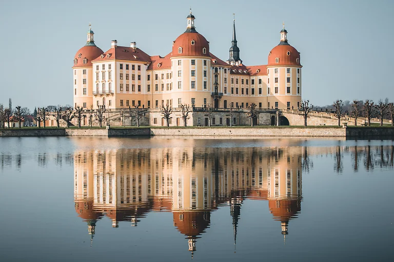 Blick auf Schloss Moritzburg mit barocker Architektur und umliegender Teichlandschaft bei Tageslicht.