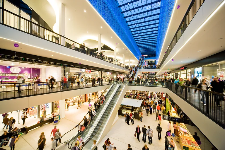 Zahlreiche Menschen beim Einkaufen in der Centrum Galerie Dresden mit Läden und Rolltreppe im Bild.
