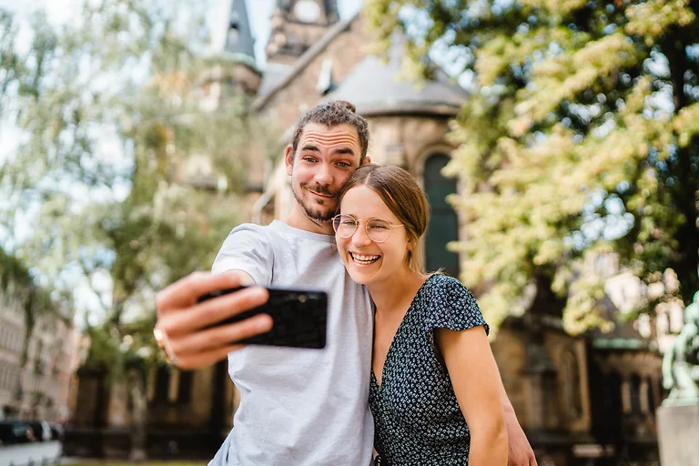 Ein Paar macht ein Selfie vor einer Kirche in der Altstadt von Dresden.