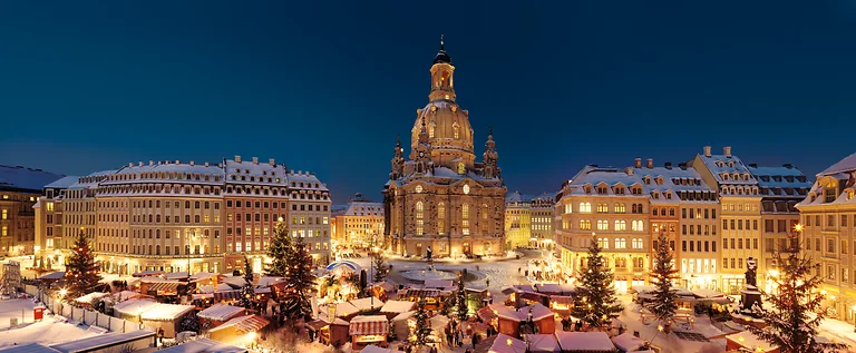 Abendlicher Blick von der Heinrich Schütz Residenz auf den festlich beleuchteten Neumarkt mit Frauenkirche und Weihnachtsmarkt.