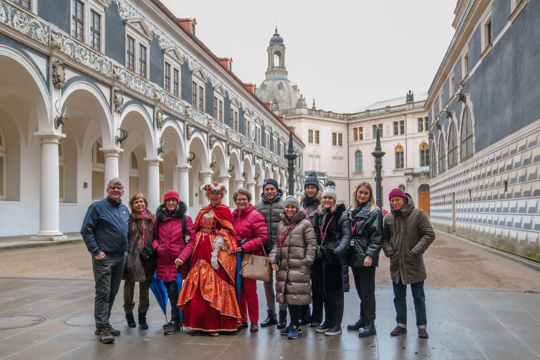 Gruppenbild im Stallhof Dresden mit einer als Gräfin Cosel verkleideten Stadtführerin. Die Gruppe steht im historischen Innenhof mit den Arkaden im Hintergrund.