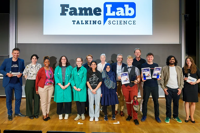 Alle Teilnehmerinnen, Teilnehmer, Juroren und moderierenden Personen des FameLab 2026 stehen gemeinsam auf der Bühne für das Gruppenbild.