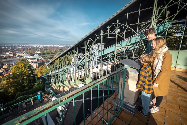 Familie steht an der Schwebebahn mit Blick über Dresden und das Blaue Wunder.